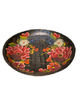 Load image into Gallery viewer, A Mexican round black decorative tray or plate featuring hand-painted floral designs in red, pink, blue, white, and green, photographed against a dark background.