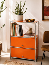 Load image into Gallery viewer, Orange two-drawer storage cabinet with polished chrome tubular frame and open upper display shelf.