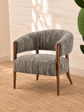 Load image into Gallery viewer, Abby charcoal grey textured bouclé accent chair with curved wraparound backrest, cushioned seat and exposed brown solid wood legs.