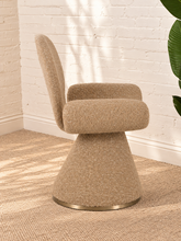 Load image into Gallery viewer, Adler fully upholstered sand dining chair with rounded back, curved wraparound seat, pedestal base, and brushed brass accent.