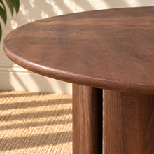 Load image into Gallery viewer, Amari round dining table in natural brown Mindi wood with sculptural rounded column pedestal base and visible wood grain.