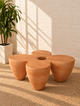 Load image into Gallery viewer, Aster sculptural coffee table in Amber fiber-reinforced concrete with four rounded pedestal forms and a distinctive central tabletop opening.