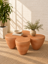 Load image into Gallery viewer, Aster sculptural coffee table in Amber fiber-reinforced concrete with four rounded pedestal forms and a distinctive central tabletop opening.