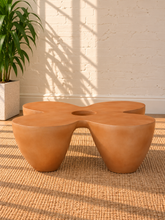 Load image into Gallery viewer, Aster sculptural coffee table in Amber fiber-reinforced concrete with four rounded pedestal forms and a distinctive central tabletop opening.