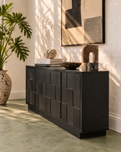 Load image into Gallery viewer, A modern black wooden console table with a geometric block pattern, styled in a bright room with a potted plant, books, and wall art.