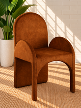 Load image into Gallery viewer, Bailey upholstered dining chair in Burnt Cognac velvet with curved arms and sculptural contemporary frame