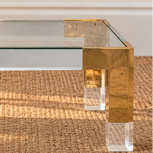 Load image into Gallery viewer, Cindy rectangular coffee table with clear glass top, polished gold stainless steel frame, and transparent acrylic legs.