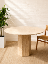 Load image into Gallery viewer, Modern round travertine dining table with ivory stone top and sculptural single pedestal base.