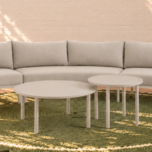 Load image into Gallery viewer, Elara curved outdoor sectional sofa in Warm Stone with plush cushions, slim aluminum frame, woven rope details, and two round nesting tables