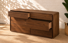 Load image into Gallery viewer, Finley six-drawer dresser in warm walnut with natural wood grain, rounded corner frame and handle-free push-to-open drawer fronts.