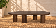 Load image into Gallery viewer, Henry solid oak coffee table in Natural Brown with organic rounded tabletop, four cylindrical legs, and prominent natural wood grain.