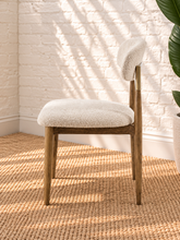 Load image into Gallery viewer, Kenna dining chair with off-white bouclé upholstered seat and rounded backrest, warm wood frame and brass-toned backrest caps.