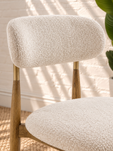 Load image into Gallery viewer, Kenna dining chair with off-white bouclé upholstered seat and rounded backrest, warm wood frame and brass-toned backrest caps.