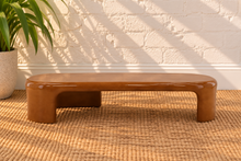 Load image into Gallery viewer, Klarisse caramel high-gloss concrete coffee table with elongated rounded top and sculptural waterfall-style supports.