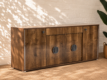 Load image into Gallery viewer, Maren Italian four-door credenza with gloss-finished rovere wood grain, center drawer, and chrome and black C-shaped hardware.