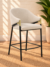Load image into Gallery viewer, Image 1 of 4: Melani upholstered counter stool in Pearl Oat linen with curved back, black metal legs, gold accents, and footrest