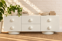 Load image into Gallery viewer, Norris Ivory buffet credenza with oversized orb knobs, central drawers, cabinet storage, and rounded pedestal base