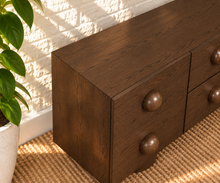 Load image into Gallery viewer, Norris Warm Walnut buffet credenza with oversized orb knobs, central drawers, cabinet storage, and sculptural pedestal base