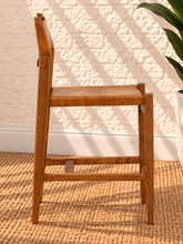 Load image into Gallery viewer, Nova counter stool in natural brown genuine leather with a tall teak wood frame, leather seat and backrest, footrest, and buckle strap detail.