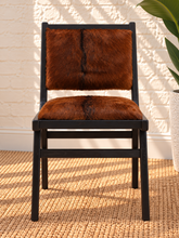 Load image into Gallery viewer, Odessa dining chair in natural chestnut genuine goat hide with a tall upholstered back, rounded seat, and exposed teak wood frame.