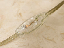 Load image into Gallery viewer, A close-up of a clear plastic electrical switch connector on a beige marble-textured surface.
