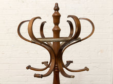 Load image into Gallery viewer, A vintage wooden coat rack with multiple curved arms and a central pedestal, shown against a white painted brick wall.