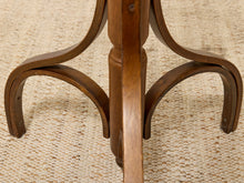 Load image into Gallery viewer, Close-up of the curved wooden legs and central pedestal of a dark brown wooden table on a textured beige woven rug.