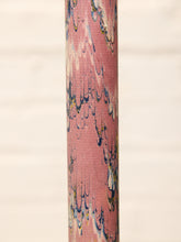 Load image into Gallery viewer, A close-up of a cylindrical product featuring a pink marbled pattern with blue, white, and yellow swirls, set against a soft, light beige background.