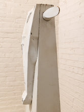 Load image into Gallery viewer, A tall, narrow white wooden wall-mounted hook or peg with a rounded oval head, shown against a white painted brick wall.