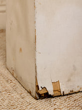 Load image into Gallery viewer, A close-up of a distressed, vintage-style off-white wooden box corner with peeling paint and exposed wood, resting on a woven beige jute rug.