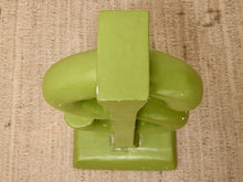 Load image into Gallery viewer, A glossy light green decorative sculpture or figurine with a blocky, geometric design, photographed from directly above on a textured beige fabric background.