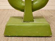 Load image into Gallery viewer, A close-up of a green painted wooden furniture base or pedestal with a rectangular flared bottom and curved upper structure, shown on a woven beige rug.