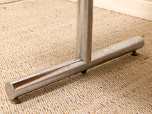 Load image into Gallery viewer, Close-up of a polished metal table leg and base on a beige woven rug.