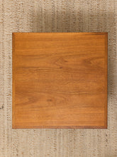 Load image into Gallery viewer, A square wooden board or tray with a warm medium-brown wood grain finish, photographed from directly above on a textured beige woven rug.