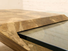 Load image into Gallery viewer, Close-up of a stone-look table top with a recessed glass panel, showing natural tan and brown marbled texture and a black glass edge.