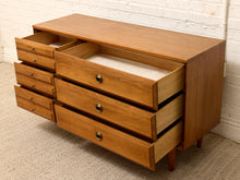 Load image into Gallery viewer, Mid-century modern wooden chest of drawers with six drawers, some open to show a light beige interior lining, set against a white brick wall and textured carpet.