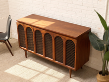 Load image into Gallery viewer, Mid-century modern wooden sideboard cabinet with five arched wire-front doors, shown in a styled room setting against a white brick wall.