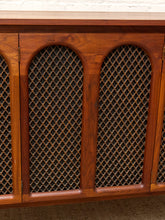 Load image into Gallery viewer, Close-up of a wooden cabinet with three arched door panels covered in a woven cane or rattan lattice pattern, set against a white brick wall and neutral floor.