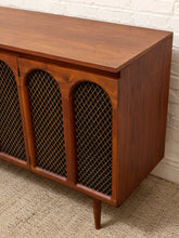 Load image into Gallery viewer, Mid-century modern wooden sideboard cabinet with three arched cane screen doors and tapered legs, shown against a white brick wall and beige carpet.