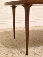 Load image into Gallery viewer, Close-up of a dark brown wooden table with tapered legs, set on a textured beige rug against a white brick wall.