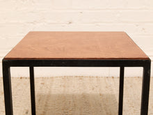 Load image into Gallery viewer, A square side table with a warm medium-brown wood grain top and a black metal frame, set against a white brick wall and light beige rug.