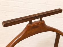 Load image into Gallery viewer, Close-up of a mid-century modern wooden chair back featuring a curved brown wood frame and a rectangular wooden top rail with a visible 'Schiefe' brand engraving, set against a white brick wall background.