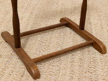 Load image into Gallery viewer, Close-up of a wooden stool base with two turned legs and a square support frame, resting on a textured beige woven rug.