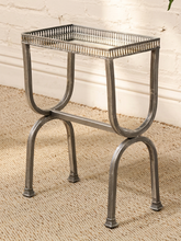 Load image into Gallery viewer, A small rectangular metal side table with a slatted open top and curved legs, shown on a woven rug against a white wall.