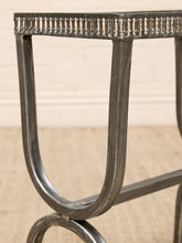 Load image into Gallery viewer, Close-up of a dark metal table leg with a decorative beaded top edge, set against a light beige wall and textured floor.