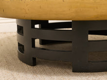 Load image into Gallery viewer, Close-up of a round coffee table with a light natural wood top and a black metal circular base, shown on a textured beige rug.