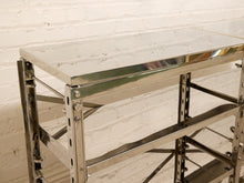 Load image into Gallery viewer, A stainless steel industrial shelving unit with a clear glass top, set against a white brick wall background.