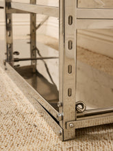 Load image into Gallery viewer, Close-up of a polished stainless steel shelving unit corner with adjustable pegs and a metal support bracket, resting on a beige textured carpet.