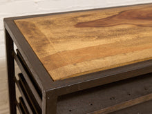 Load image into Gallery viewer, Close-up of a rustic industrial table featuring a warm-toned wood top with a dark metal frame and slatted side shelves.