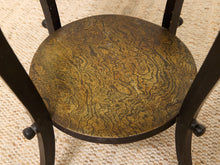 Load image into Gallery viewer, A close-up of a round wooden chair seat with a swirling, marbled golden-brown wood grain pattern, supported by a black metal frame on a woven beige rug.